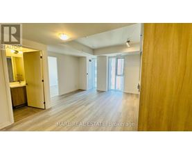 A spacious room with wooden flooring and white walls, with a doorway leading to another room.