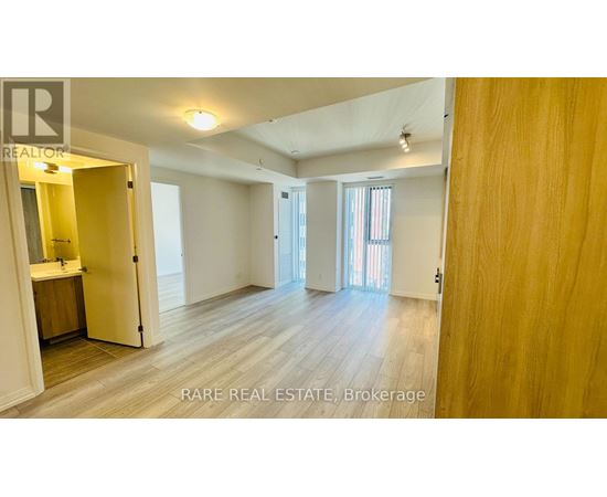 A spacious room with wooden flooring and white walls, with a doorway leading to another room.