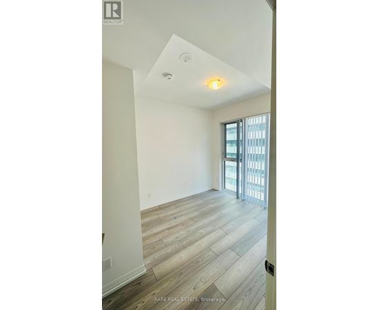 A room with a slanted ceiling and a door leading to a balcony.