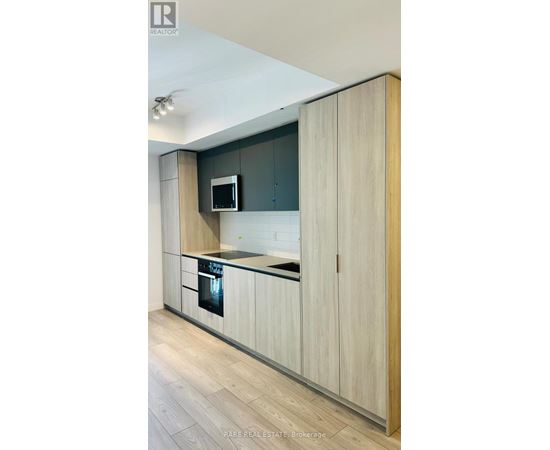 A modern kitchen with wooden cabinets and a microwave above the stove.