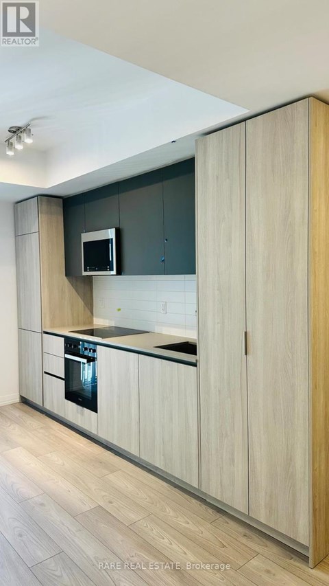 A modern kitchen with wooden cabinets and a microwave above the stove.