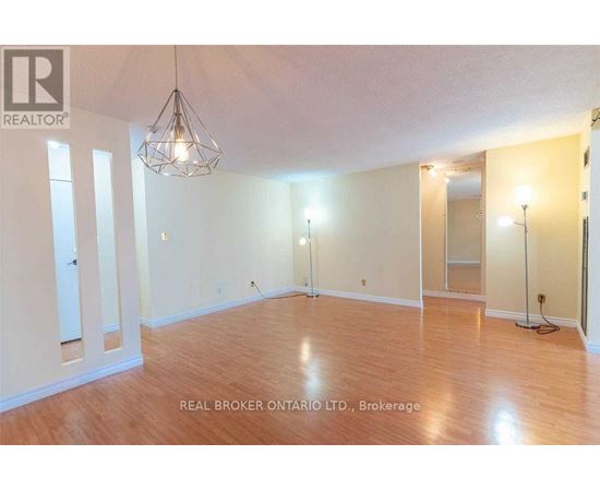 A large empty room with wooden floors and a chandelier.