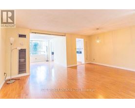 A spacious room with wooden flooring and a large window.