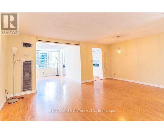 A spacious room with wooden flooring and a large window.