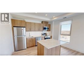 A modern kitchen with wooden cabinets and a stainless steel refrigerator.
