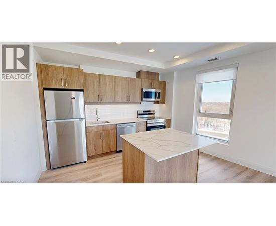 A modern kitchen with wooden cabinets and a stainless steel refrigerator.