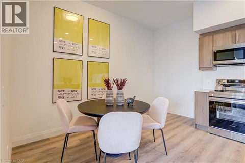 A dining room with a table and chairs and a fridge in the corner.