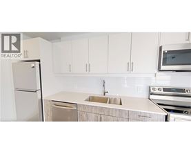 A kitchen with white cabinets and a white fridge.