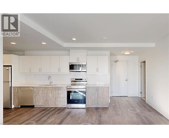 A modern kitchen with white cabinets and a wooden floor.