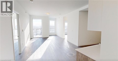 A spacious, empty room with a large window and a door leading to another room.
