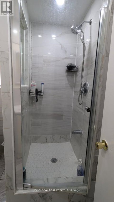 A shower with a glass door and a marble floor.