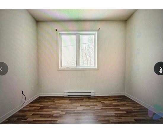 A room with a window and wooden flooring.