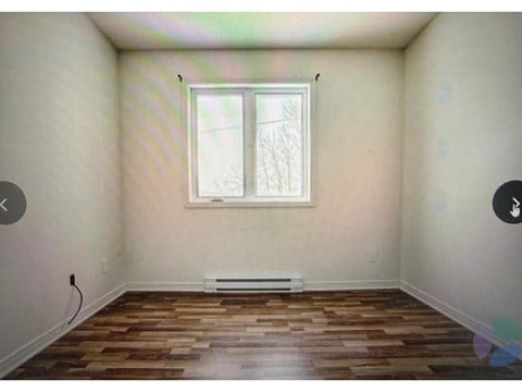 A room with a window and wooden flooring.