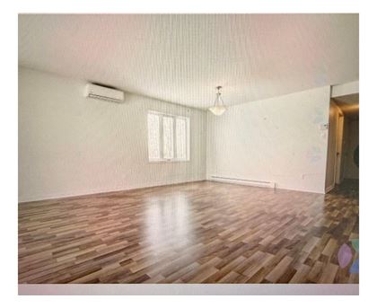 A room with wooden flooring and a window with blinds.