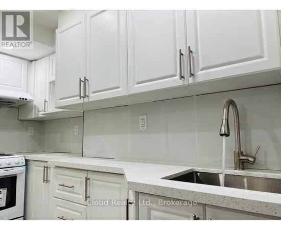A kitchen with white cabinets and a stainless steel sink.