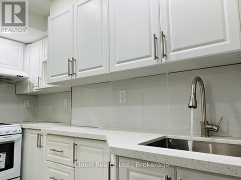 A kitchen with white cabinets and a stainless steel sink.