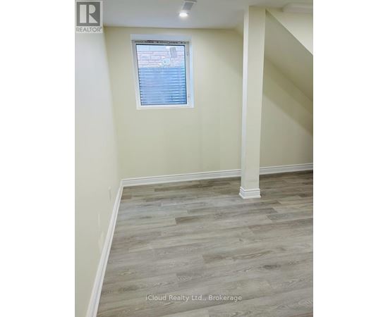 A room with wooden flooring and a window with blinds.