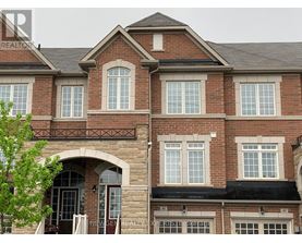 A brick house with a balcony and a tree in front.