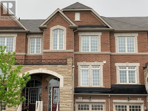 A brick house with a balcony and a tree in front.