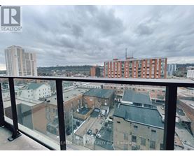 A view from a balcony overlooking a cityscape with buildings and a cloudy sky.