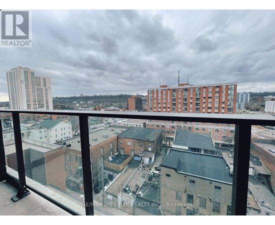 A view from a balcony overlooking a cityscape with buildings and a cloudy sky.