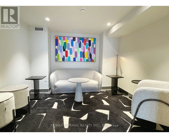A white couch sits in a room with a colorful painting on the wall.