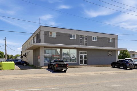 A grey building with a black truck parked in front.
