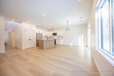 A spacious kitchen with wooden floors and white walls.