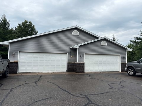 A grey house with two white garage doors.
