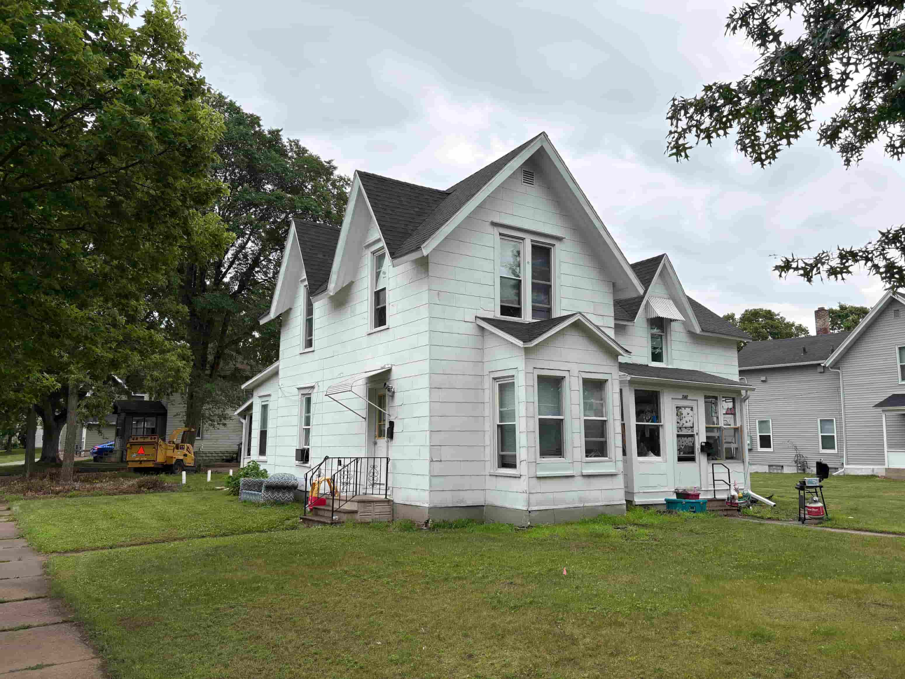 A white house with a grey roof and a black chimney.