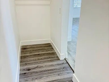 A hallway with a wooden floor and white walls.
