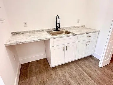 A kitchen with a marble countertop and white cabinets.