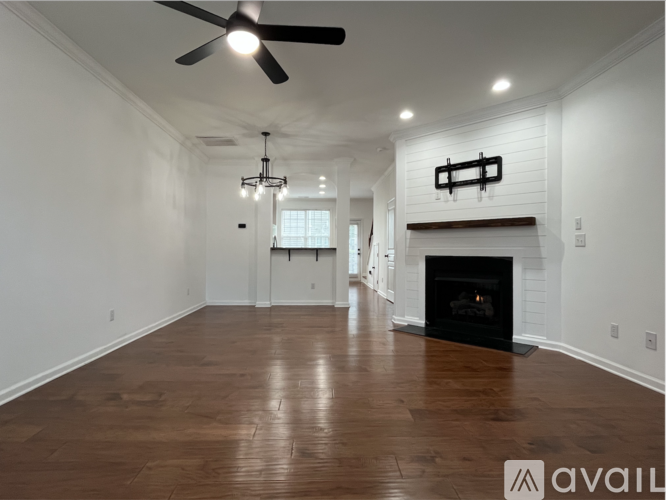 A spacious room with a fireplace and wooden flooring.