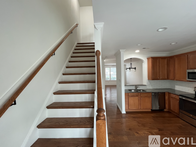 A staircase with wooden steps and handrails leads to a kitchen area.