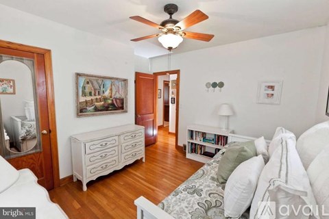 A living room with a white couch and a painting on the wall.