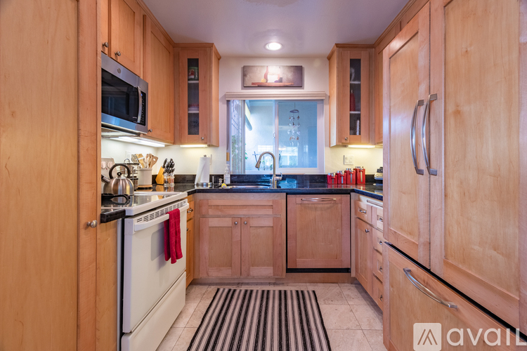 A kitchen with wooden cabinets and a striped rug on the floor.
