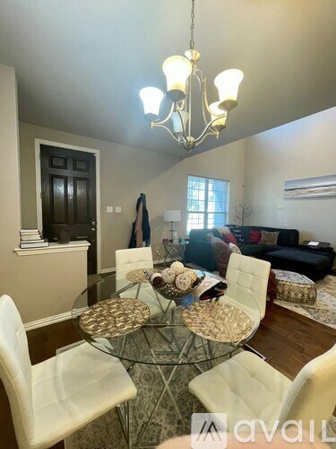 A dining room with a glass table and white chairs.