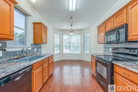 A kitchen with wooden cabinets and black appliances.