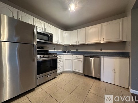 A kitchen with white cabinets and a stainless steel refrigerator.