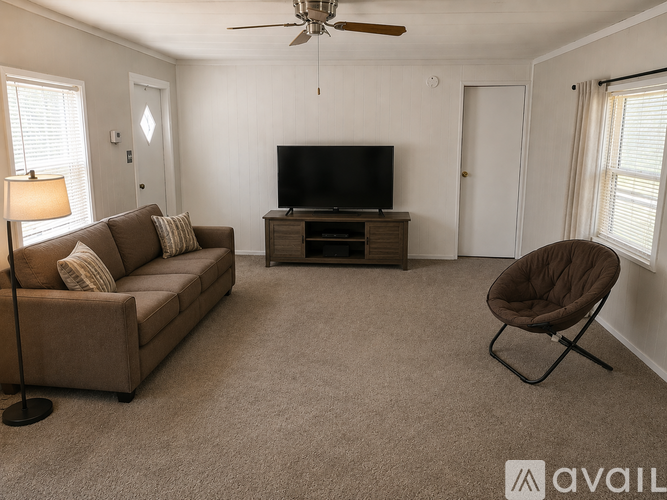 A living room with a brown couch, a television, and a ceiling fan.