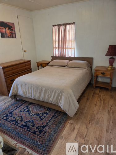 A bedroom with a bed, nightstand, and rug.