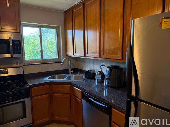 A kitchen with wooden cabinets and a stainless steel refrigerator.