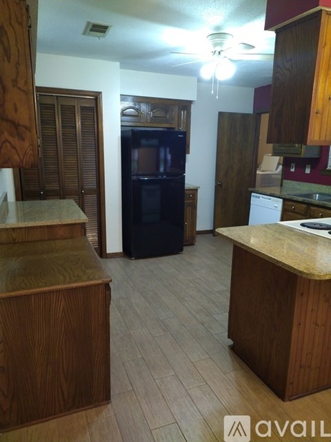 A kitchen with wooden cabinets and a black refrigerator.