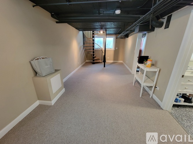 A spacious room with a carpeted floor and a staircase in the background.