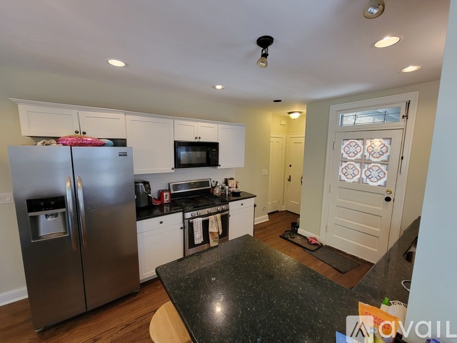 A kitchen with a black counter top and stainless steel appliances.