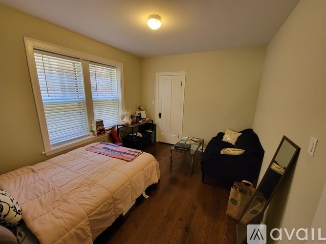 A bedroom with a bed, chair, and window.