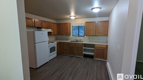 A kitchen with wooden cabinets and a white fridge is available for rent.