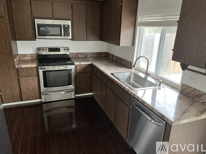 A kitchen with wooden cabinets and a stainless steel dishwasher.
