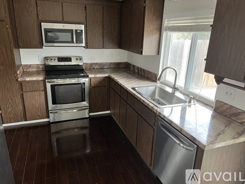 A kitchen with wooden cabinets and a stainless steel dishwasher.