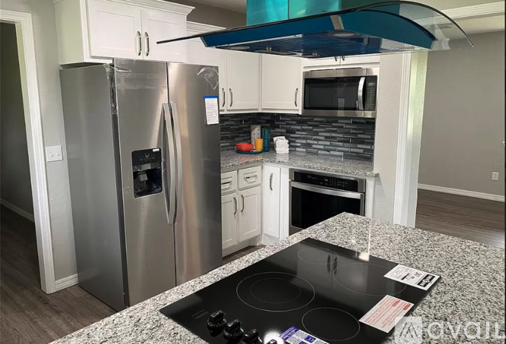 A kitchen with a stainless steel refrigerator and a black stove top.